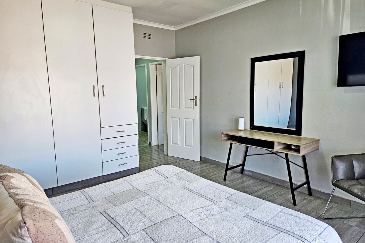 A well-maintained bedroom featuring built-in wardrobes, tiled flooring, and direct access to an adjoining bathroom.
