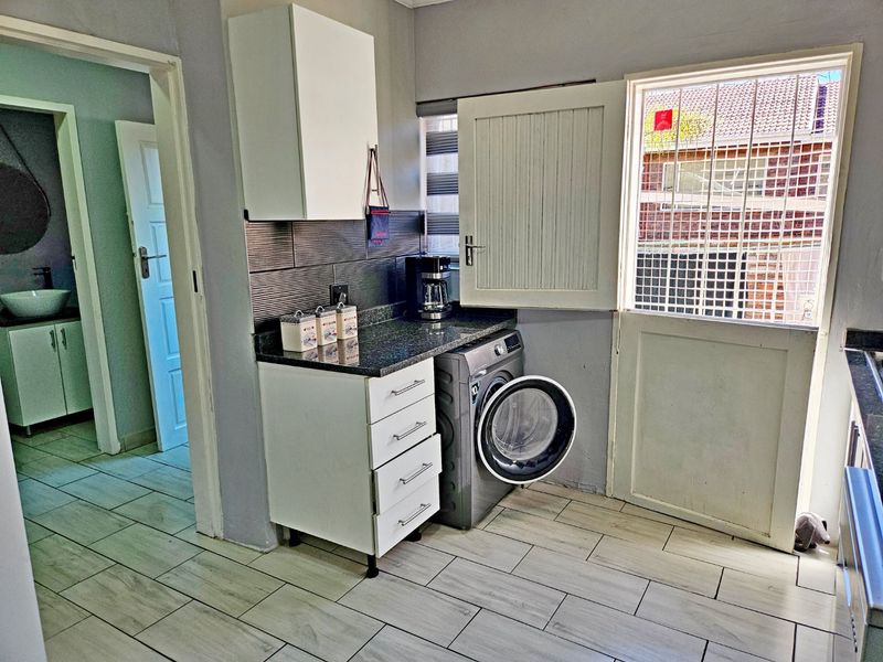 A functional laundry area featuring built-in cabinetry, granite countertops, tiled flooring, and direct access to the exterior via a secure door.