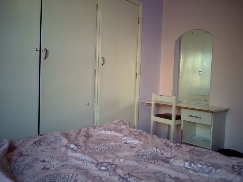 A bedroom featuring built-in cupboards and a vanity area, requiring cosmetic updates to improve the overall aesthetic and condition of the space.