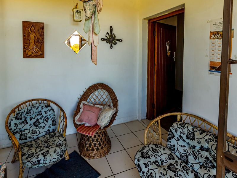 A covered patio area featuring tiled flooring and a timber door frame, providing a functional transition space between the interior and exterior.