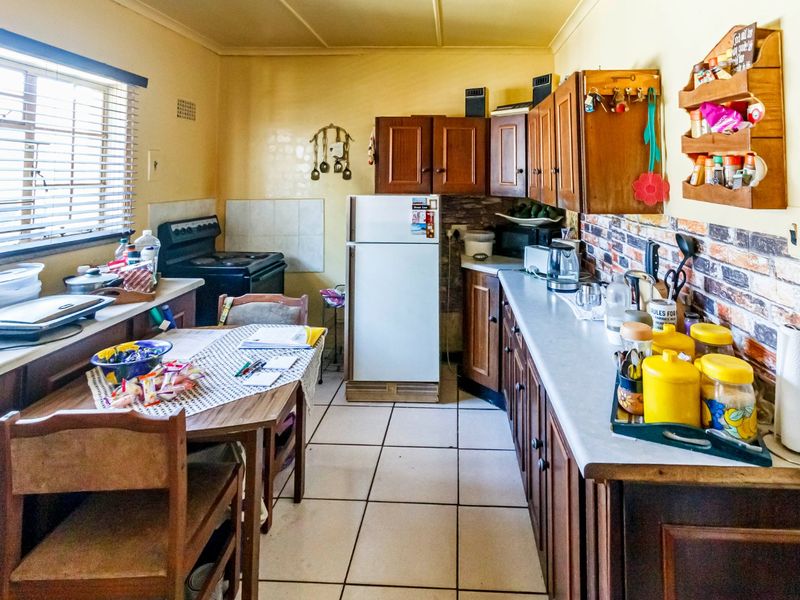 A functional kitchen featuring traditional wooden cabinetry, laminate countertops, and tiled flooring, offering a classic layout with potential for modern updates.