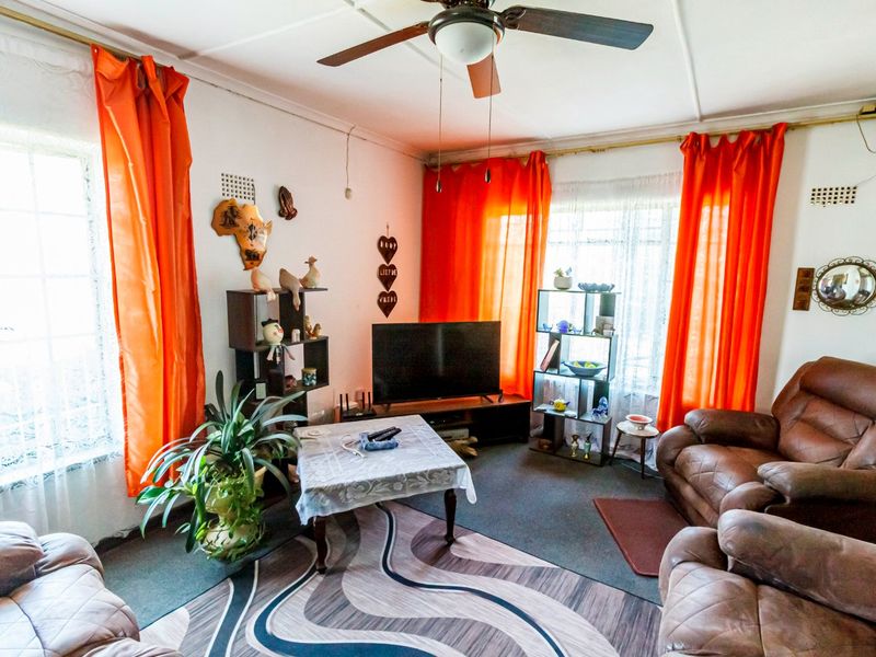 A living room featuring a ceiling fan and large windows that provide natural light.
