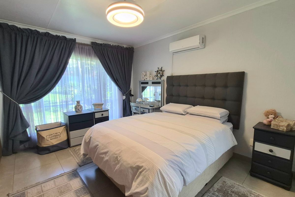 A well-maintained bedroom featuring tiled flooring, a wall-mounted air conditioning unit, and a built-in cupboard, offering a comfortable and functional living space.