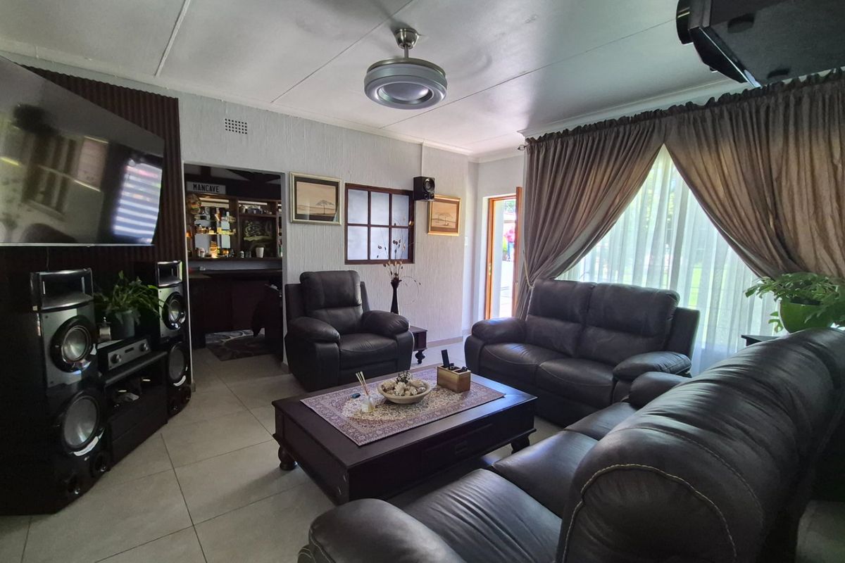 A comfortable living room featuring tiled flooring, a ceiling fan, and an internal window, providing a functional space with access to an adjacent area.