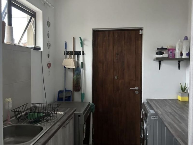 A functional laundry room featuring a stainless steel sink, laminate countertops, and a timber door, providing practical utility space.