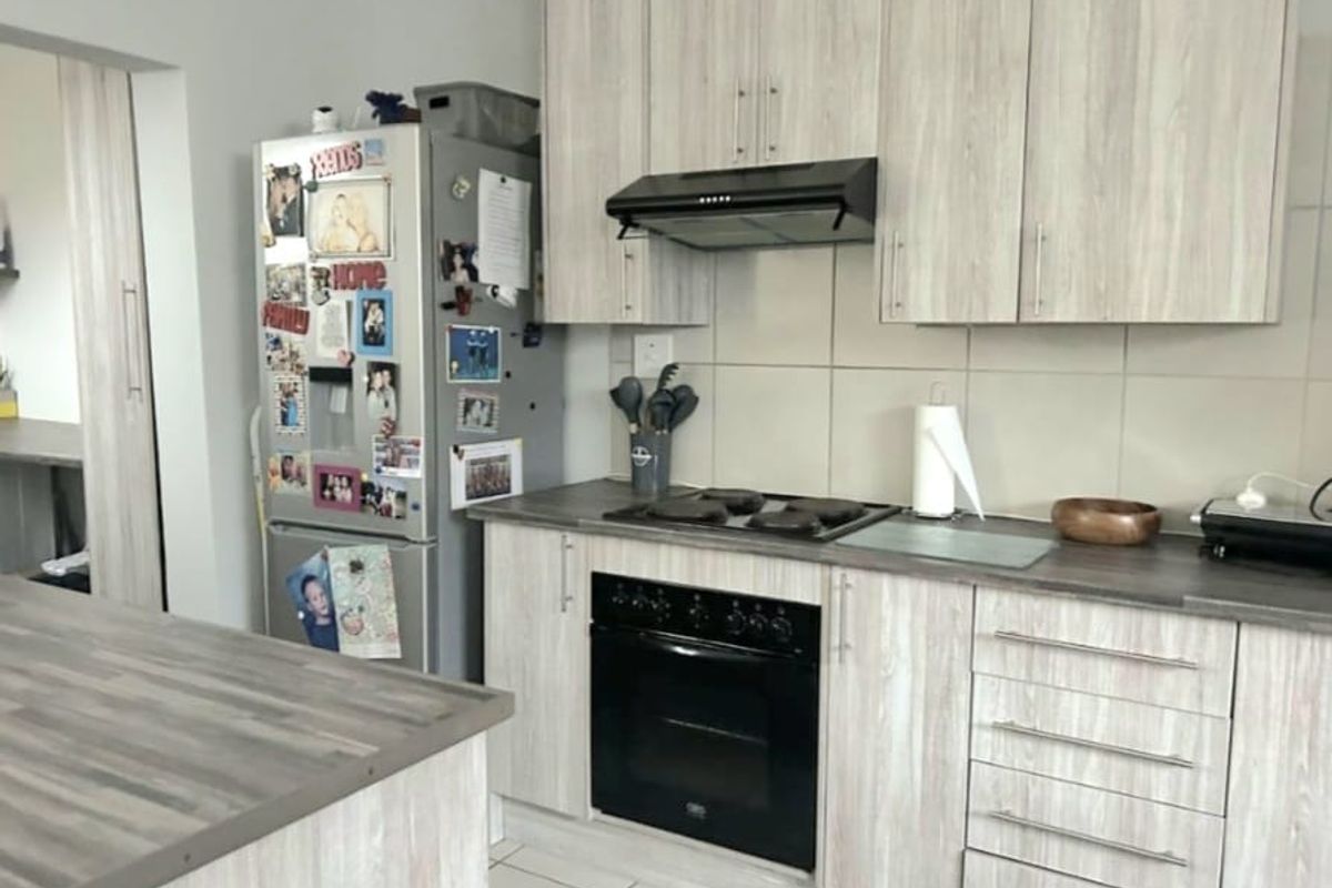 A functional kitchen featuring light wood-grain cabinetry, dark laminate countertops, a built-in oven, and a tiled backsplash.
