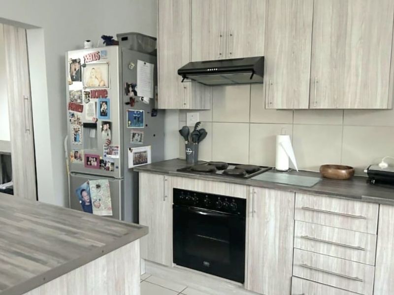 A functional kitchen featuring light wood-grain cabinetry, dark laminate countertops, a built-in oven, and a tiled backsplash.