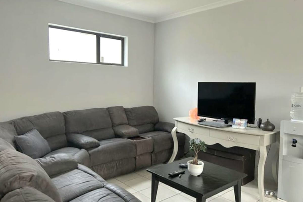 A living room featuring neutral wall paint, tiled flooring, and a horizontal window, providing a functional and well-lit space.