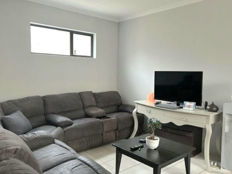 A living room featuring neutral wall paint, tiled flooring, and a horizontal window, providing a functional and well-lit space.