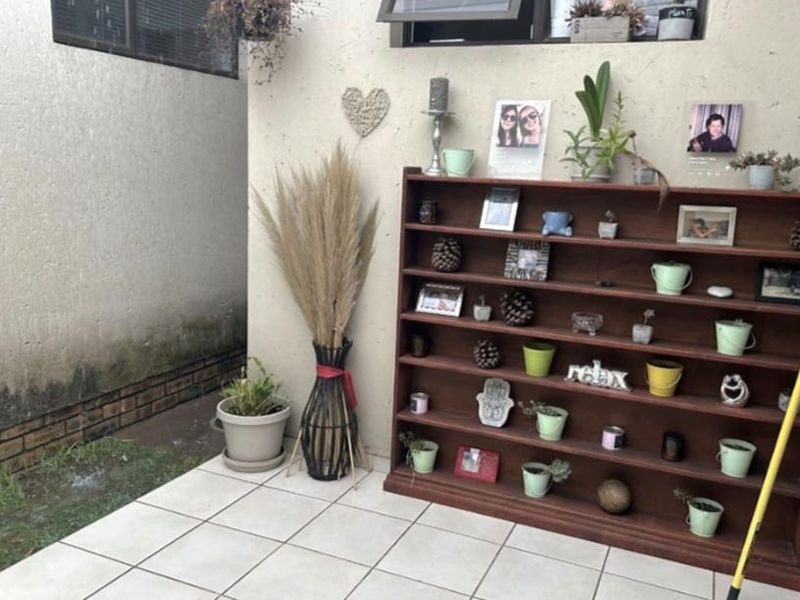 A small outdoor patio area featuring tiled flooring and an exterior wall showing signs of moisture staining and dampness.