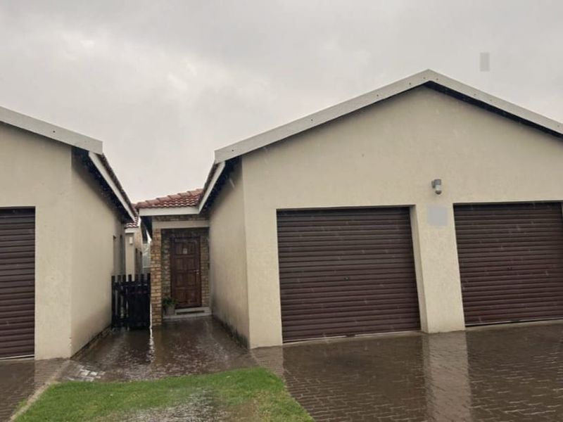 Front elevation of the property featuring a double garage and a single garage with roller shutter doors, set against a paved driveway.