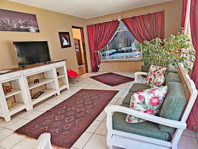 A living room featuring tiled flooring and a large window, providing a functional space with direct access to adjacent rooms.