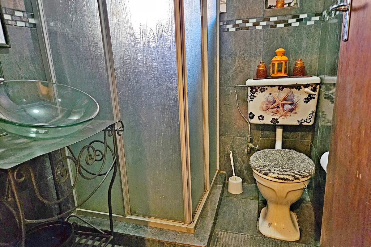 Compact bathroom featuring a glass vessel sink with wrought iron vanity, a shower enclosure, and tiled finishes throughout.