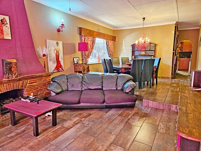 Open-plan living and dining area featuring a prominent stone-clad fireplace, raised dining platform, and wood-look tiled flooring throughout.