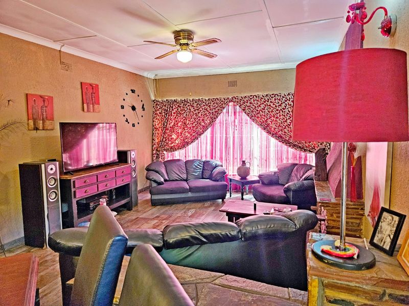 A living room featuring a coved ceiling with a central fan and a stone feature wall, providing a functional and lived-in space.