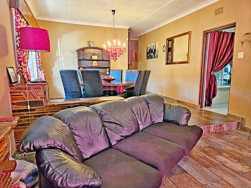 Open plan living and dining area featuring tiled flooring, a stone feature wall, and coved ceilings, providing a functional and connected living space.
