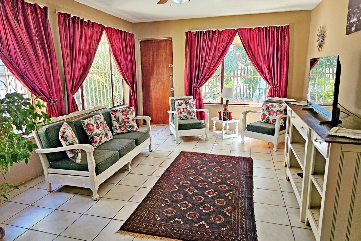 A living room featuring tiled flooring, a ceiling fan, and large windows fitted with security bars.