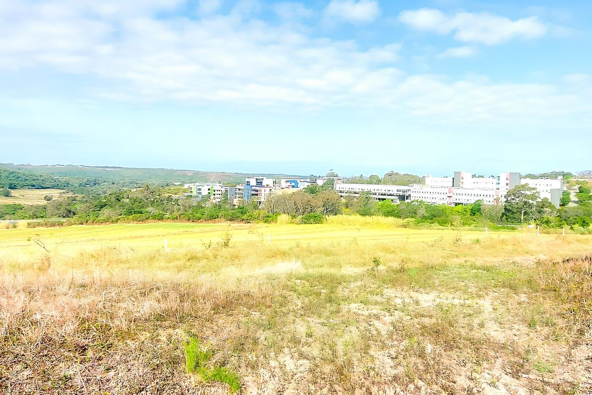 A wide-angle view of the vacant residential land, showcasing the surrounding landscape and distant urban development.