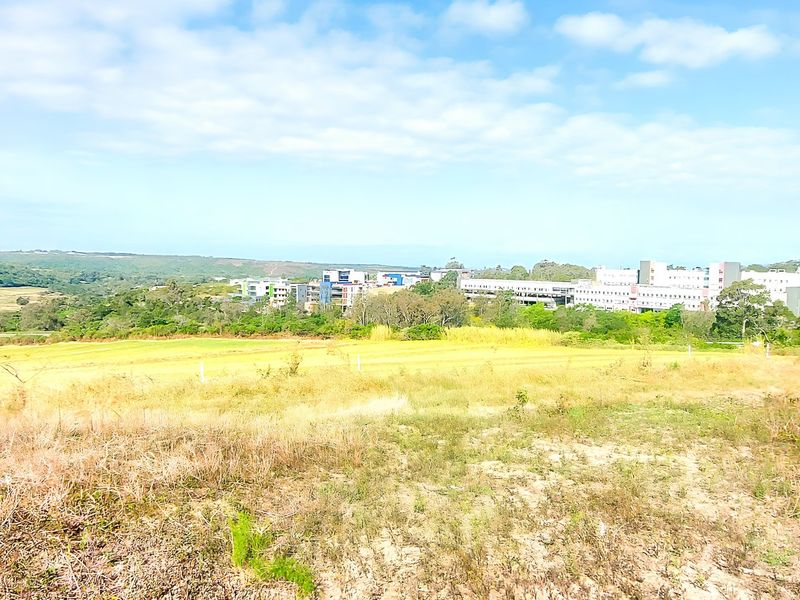 A wide-angle view of the vacant residential land, showcasing the surrounding landscape and distant urban development.