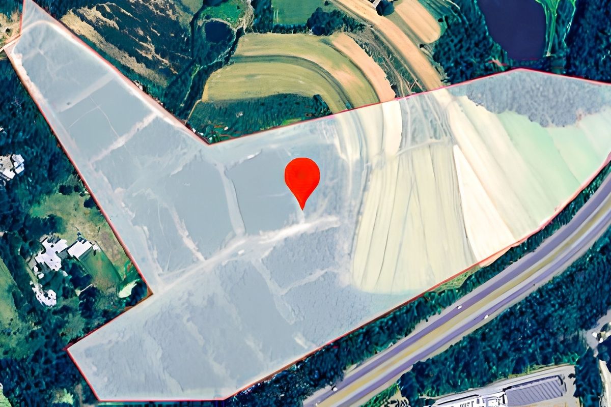 Aerial view of a large vacant residential land parcel with clearly defined boundaries and a central location marker.