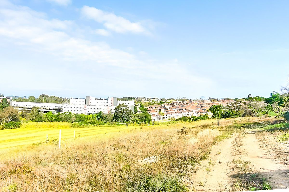 A wide-angle view of the vacant residential land, showcasing the surrounding landscape and nearby neighborhood development.