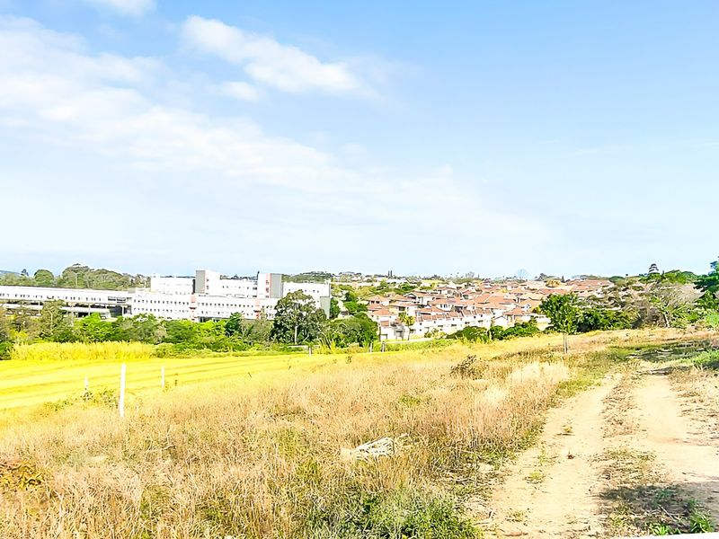 A wide-angle view of the vacant residential land, showcasing the surrounding landscape and nearby neighborhood development.