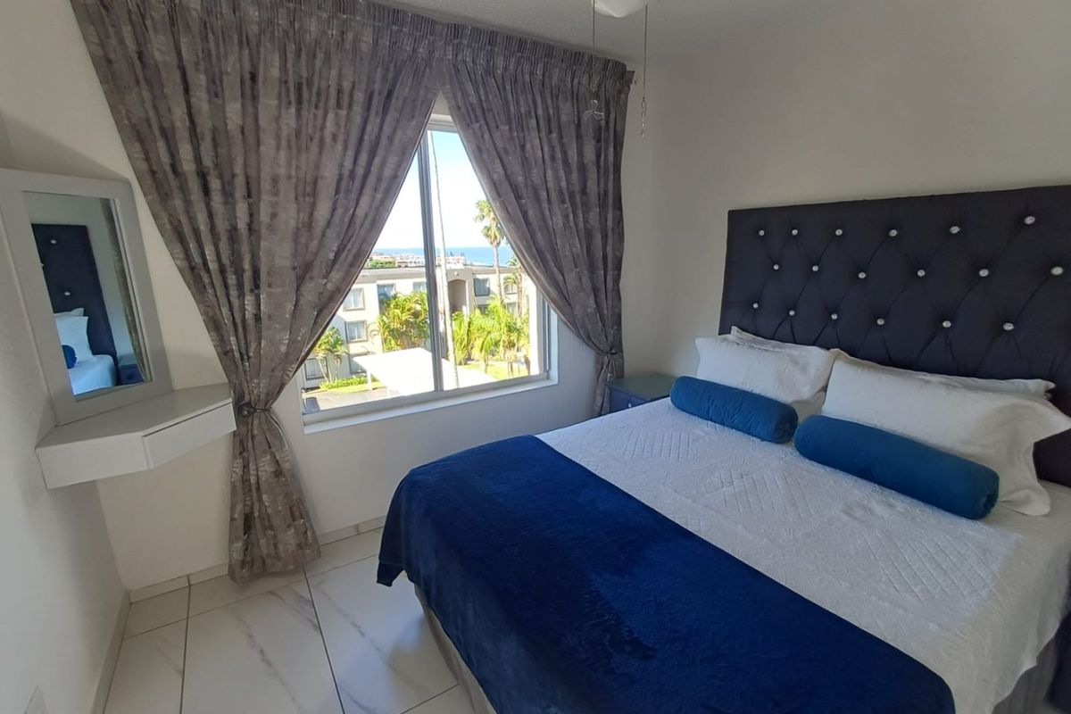 A well-maintained bedroom featuring tiled flooring, a large window with natural light, and a neutral color palette.