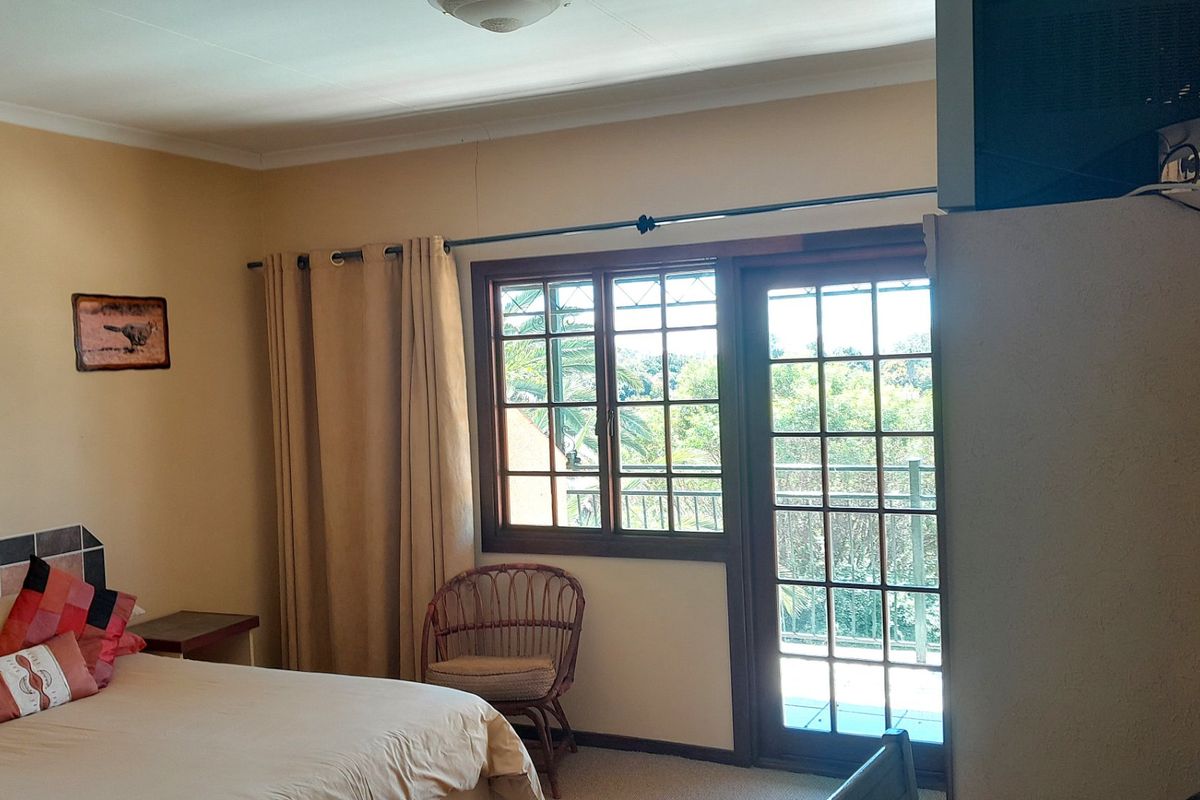 A bedroom featuring timber-framed windows and a glass door leading to an outdoor area, with a tiled headboard detail.
