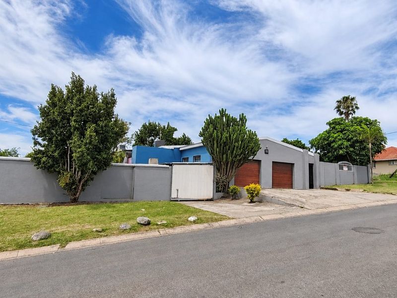 Front exterior view of the property featuring a perimeter wall, double garage with roll-up doors, and a paved driveway.