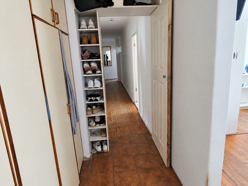 A hallway featuring built-in storage cabinetry, tiled flooring transitioning to wood, and access to adjacent living spaces.