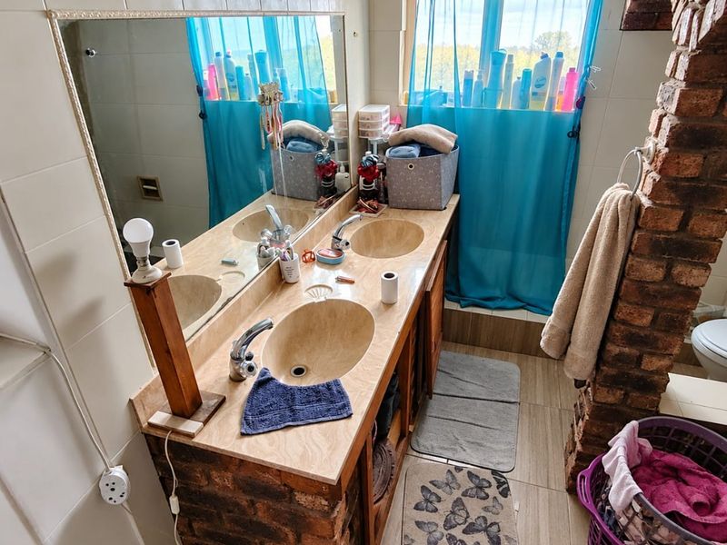 A bathroom featuring a double vanity with stone countertop, undermount sinks, and a distinctive exposed brick pillar, requiring some cosmetic updates.