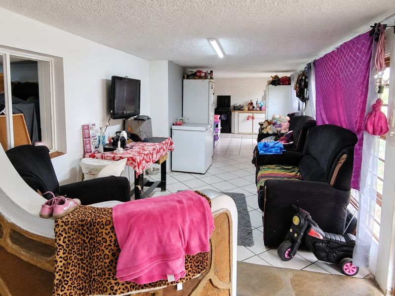 Open plan living and kitchen area featuring tiled flooring and basic cabinetry, offering a functional layout with potential for modernization.