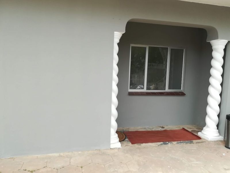A covered patio area featuring decorative spiral columns, tiled flooring, and a modern aluminium window frame, providing a clean and functional outdoor space.