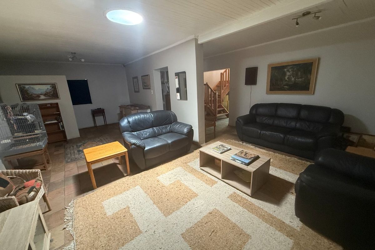 Spacious living area featuring tiled flooring, a timber ceiling with a skylight, and an open transition to a timber staircase.
