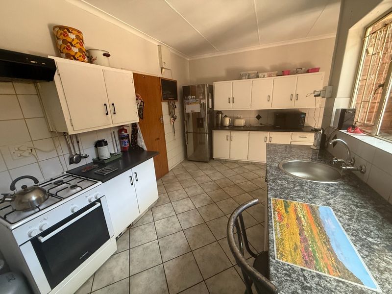 Functional kitchen featuring built-in cabinetry, gas stove with extractor, laminate countertops, and tiled flooring, offering a practical layout for daily meal preparation.