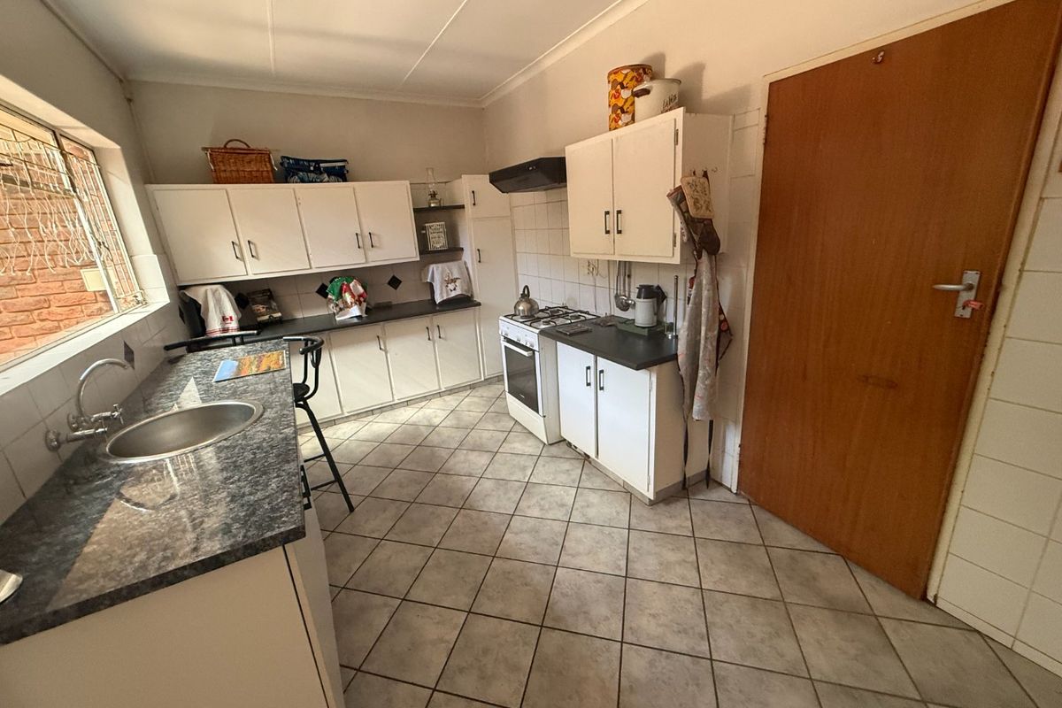 A functional kitchen featuring built-in cabinetry, laminate countertops, a gas stove with extractor fan, and tiled flooring throughout.