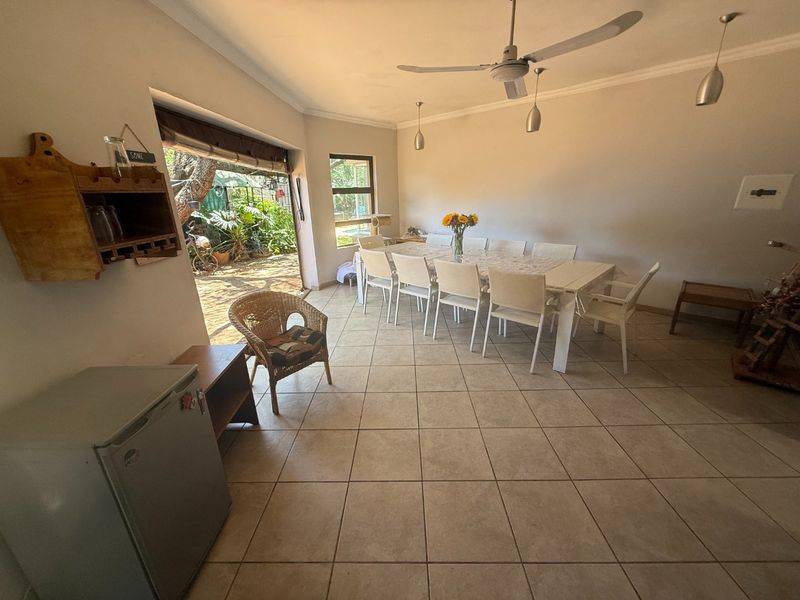 Spacious dining area featuring tiled flooring, ceiling fan, and large sliding doors providing direct access to the outdoor garden space.