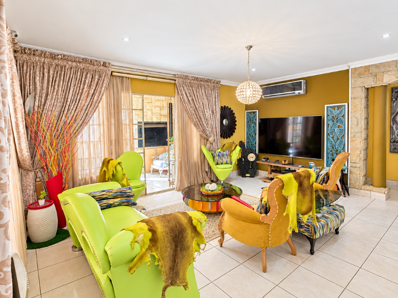 Spacious living room featuring neutral tiled flooring, a stone feature wall, and sliding glass doors providing access to the patio area.