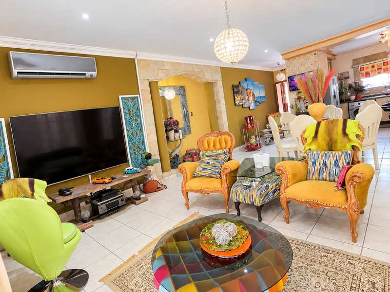 Spacious open-plan living area featuring tiled flooring, a stone-clad archway, and integrated air conditioning, flowing into an adjacent dining and kitchen space.