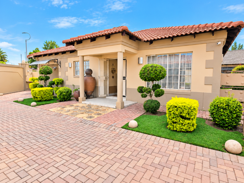 Well-maintained single-story home featuring a terracotta tiled roof, paved driveway, and a neat, landscaped front garden with a covered entrance porch.