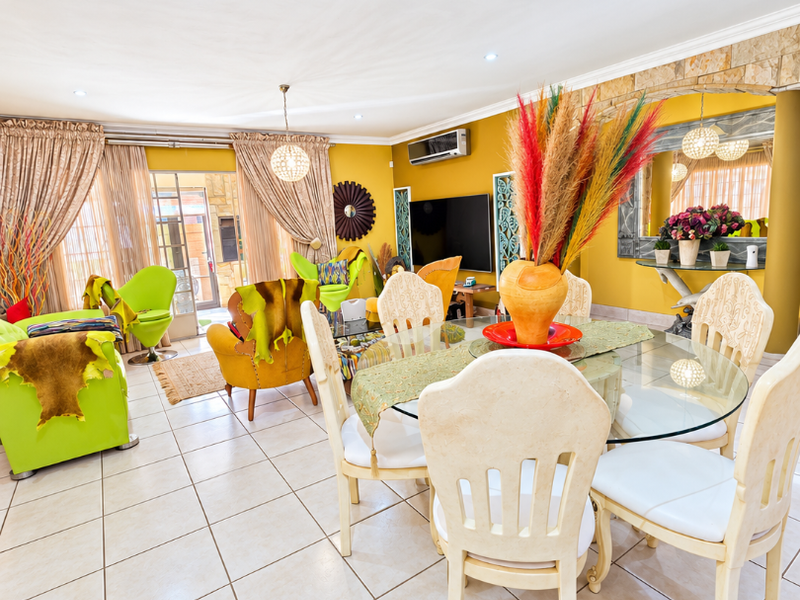 Spacious open-plan living and dining area featuring neutral tiled flooring, a stone feature wall, and direct access to the outdoor patio through sliding doors.