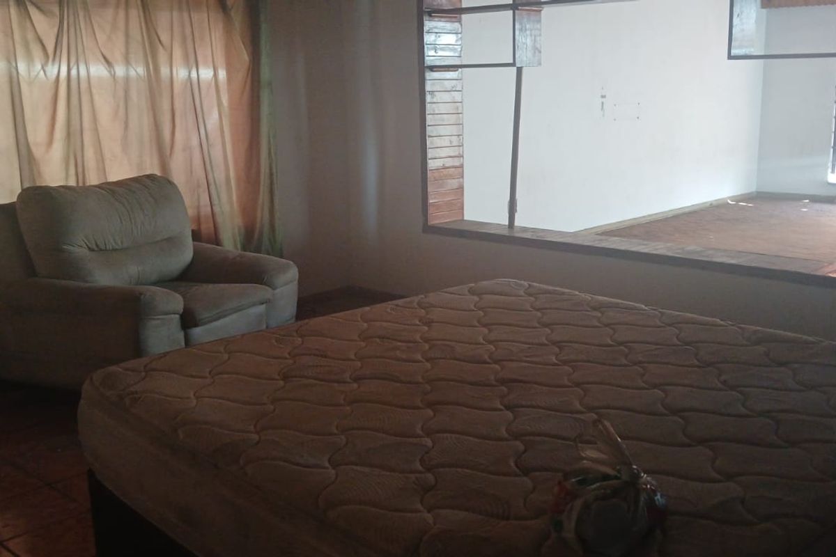 A bedroom featuring tiled flooring and a large window looking into an adjacent space, requiring cosmetic updates to improve its overall appeal.