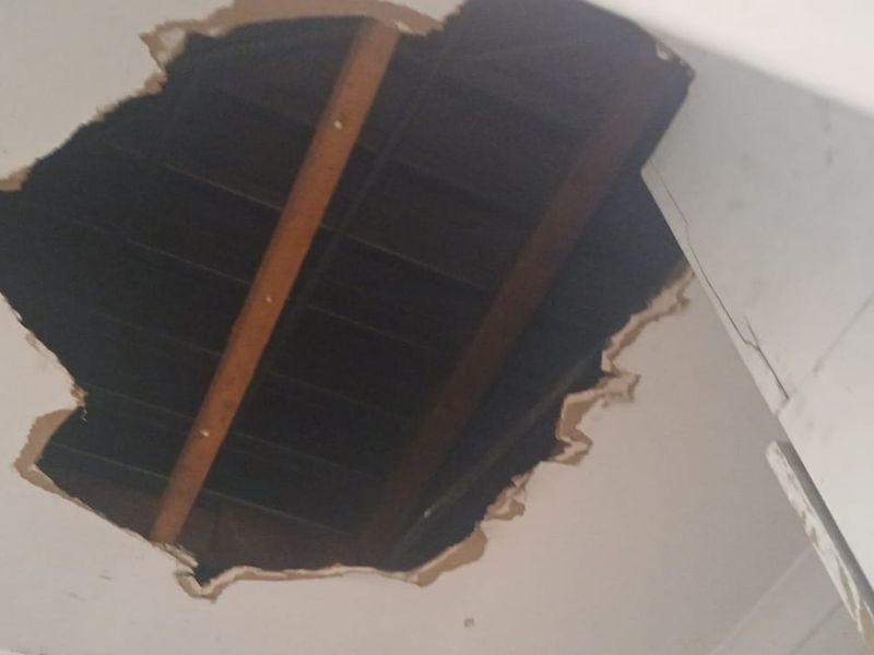 A significant hole in the ceiling exposing the structural joists above.
