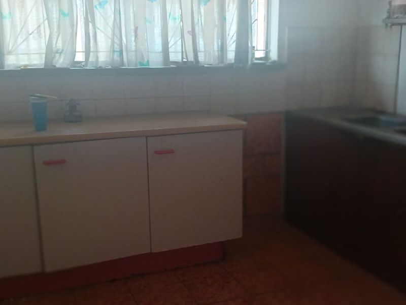A dated kitchen featuring built-in cabinetry, a double sink, and tiled splashbacks, offering significant potential for modernization and renovation.