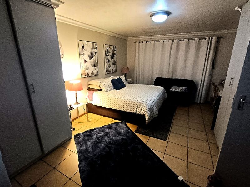 A bedroom featuring tiled flooring, a built-in wardrobe, and curtain rails, providing a functional space with standard finishes.