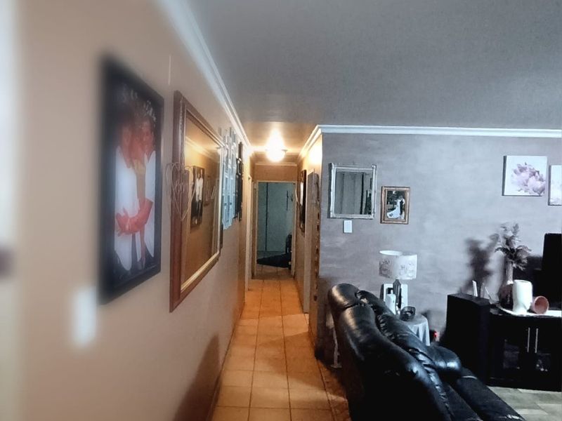 A view of the living area featuring tiled flooring and a connecting hallway, showing a standard layout with neutral wall finishes.