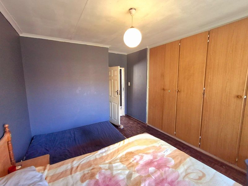 A bedroom featuring built-in wooden cupboards, parquet flooring, and coved ceilings, offering a functional space with potential for cosmetic updates.