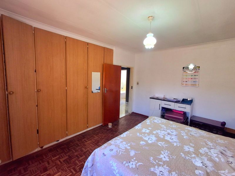 A bedroom featuring classic parquet flooring and extensive built-in wooden cabinetry, offering ample storage space and a traditional aesthetic.