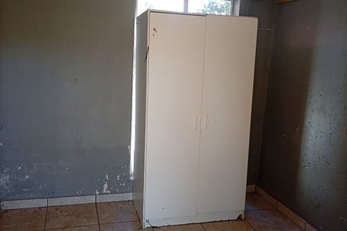 A vacant bedroom featuring tiled flooring and a window, requiring cosmetic updates to the wall finishes and general maintenance.