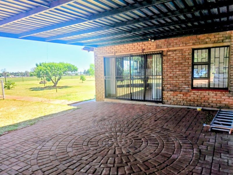 A covered outdoor patio area featuring decorative brick paving and direct access to the interior through sliding glass doors with security bars.